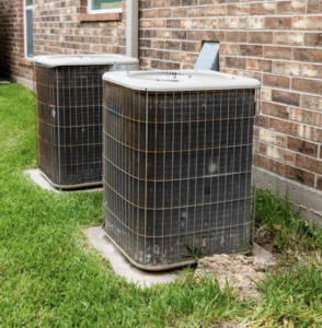 Two air conditioning units installed outside on concrete slabs.